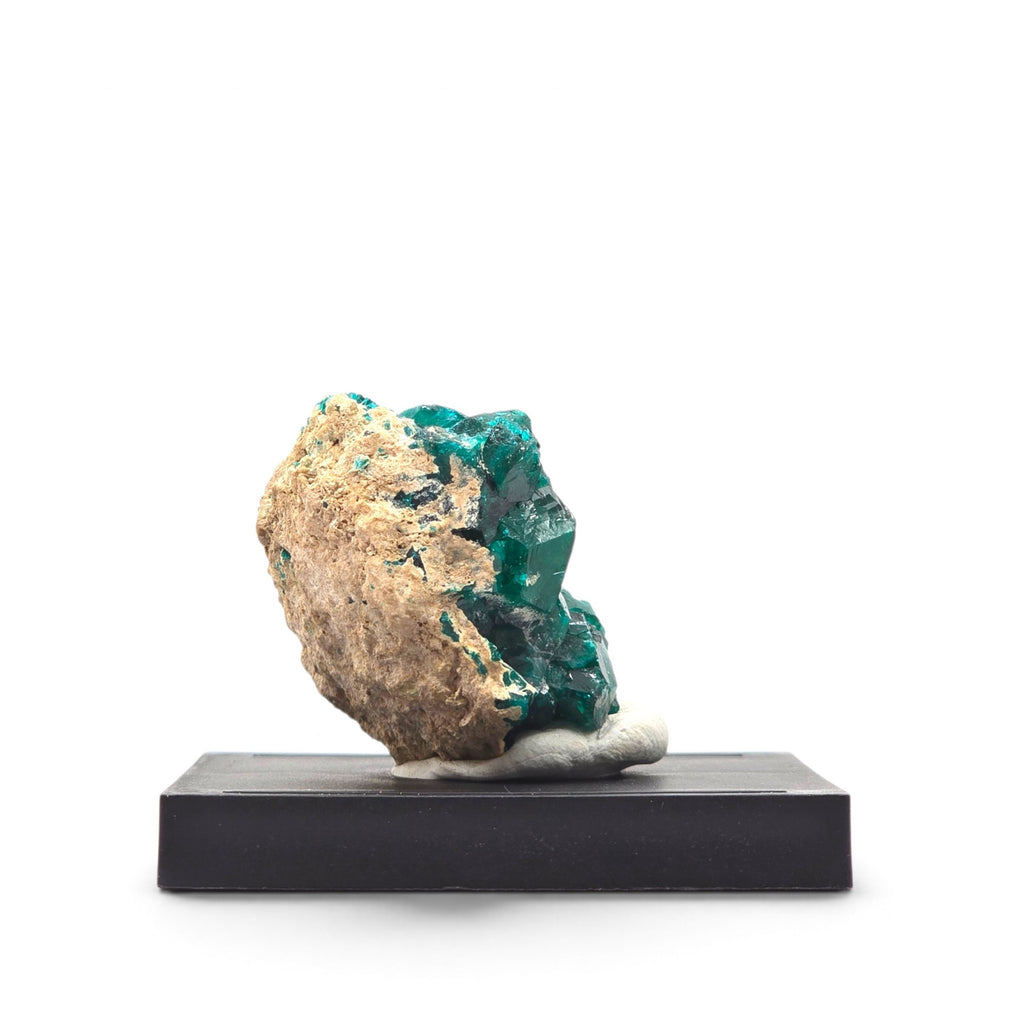 Opposite side view of dark emerald-green dioptase crystal faces beside tan matrix