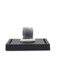Front view of a dark blue-gray blocky sapphire crystal mounted upright on a black display base