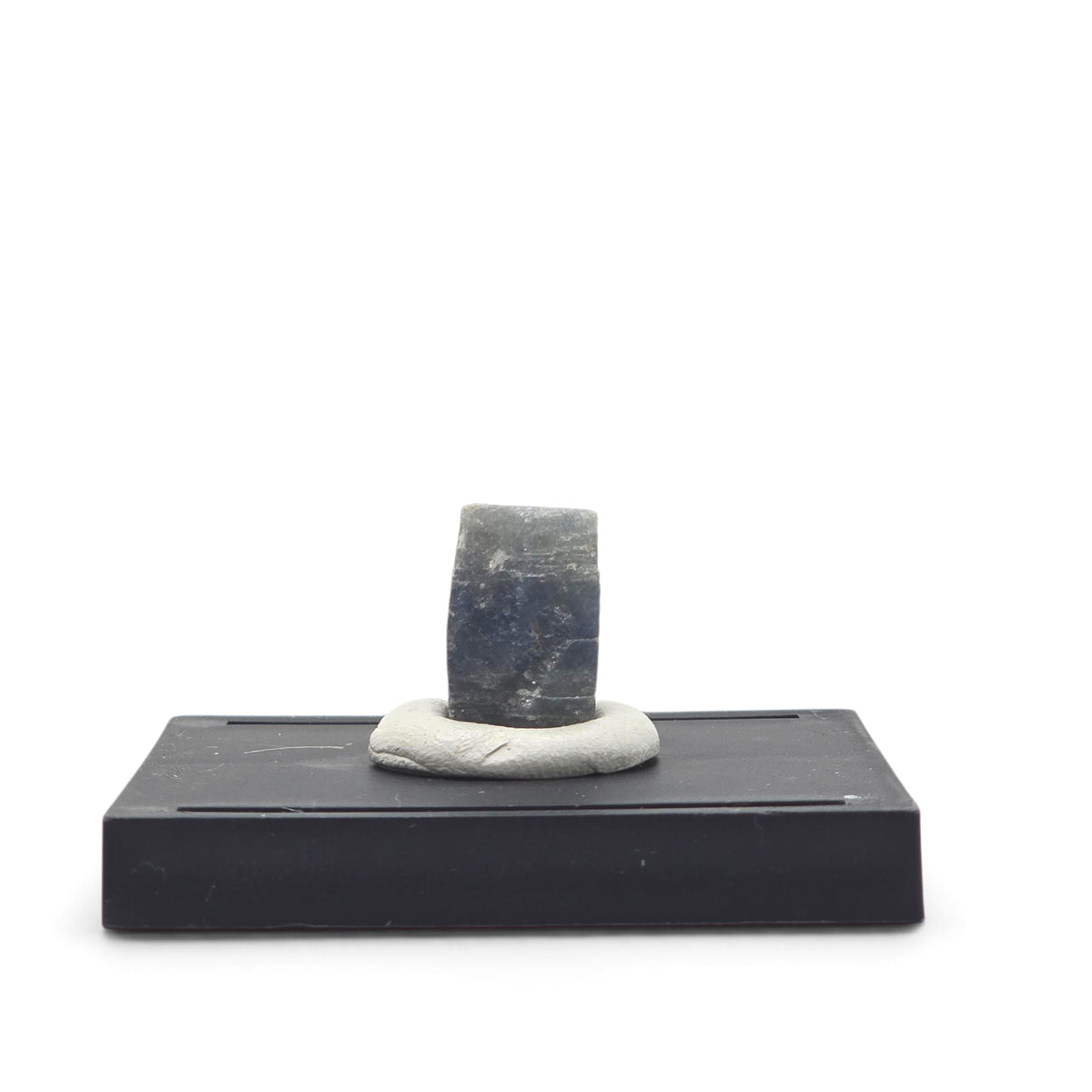 Reverse view of the blocky sapphire crystal showing dark blue-gray color and pale surface marks