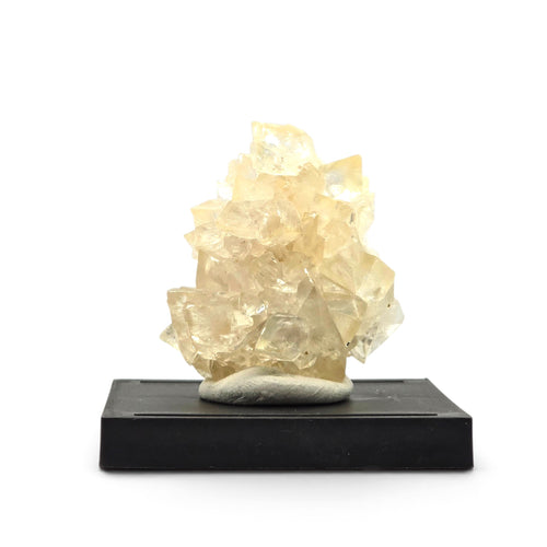 Front view of a pale honey calcite crystal cluster mounted upright on a black display base