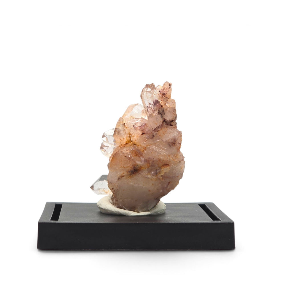 Upright pale peach quartz cluster with reddish-brown inclusions on a black display base